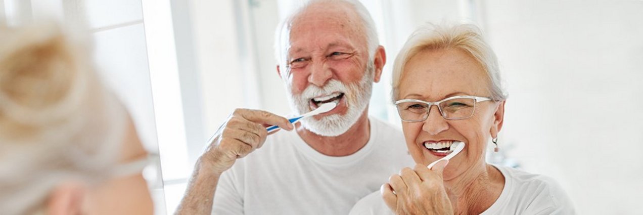 ein älteres Ehepaar putzt gemeinsam Zähne vor einem großen badezimmerspiegel ein älteres Ehepaar putzt gemeinsam Zähne vor einem großen badezimmerspiegel