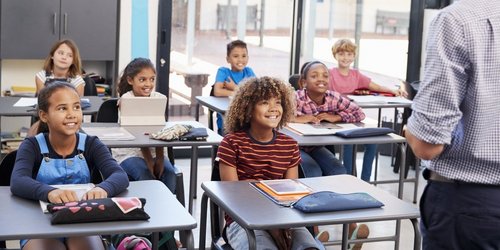 Bildung im Regionalverband Schüler mit Tablets und Schulmäppchen und Büchern hören lächelnd ihrem Lehrer zu