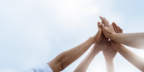 Ehrenamt Mehre Hände schlagen vor dem Himmel ein