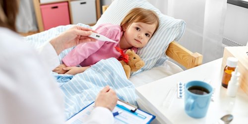 Inkeftionsschutz bei Kinder Eine Ärztin misst bei einem kranken Kind Fieber im Bett