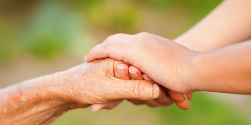 Betreuungsbehörde junge Frau hält die Hand von Seniorin