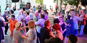 Menschen tanzen ausgelassen vor der Schlossgartenbühne zu italienischer Musik