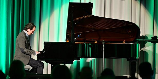 Pianist Manuel Krass gestaltete den musikalischen Rahmen. Foto: Stephan Hett/Regionalverband Saarbrücken Pianist Manuel Krass am schwarzen Flügel auf der Bühne des Festsaals.