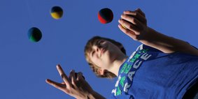 Junge jongliert mit bunten Bällen